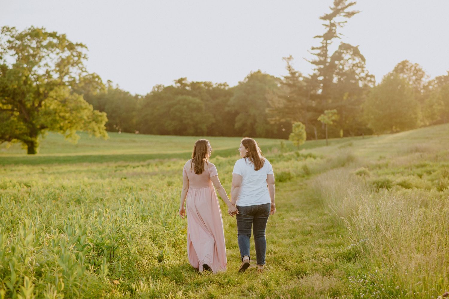 Same sex couple walking during maternity session at Golden hour