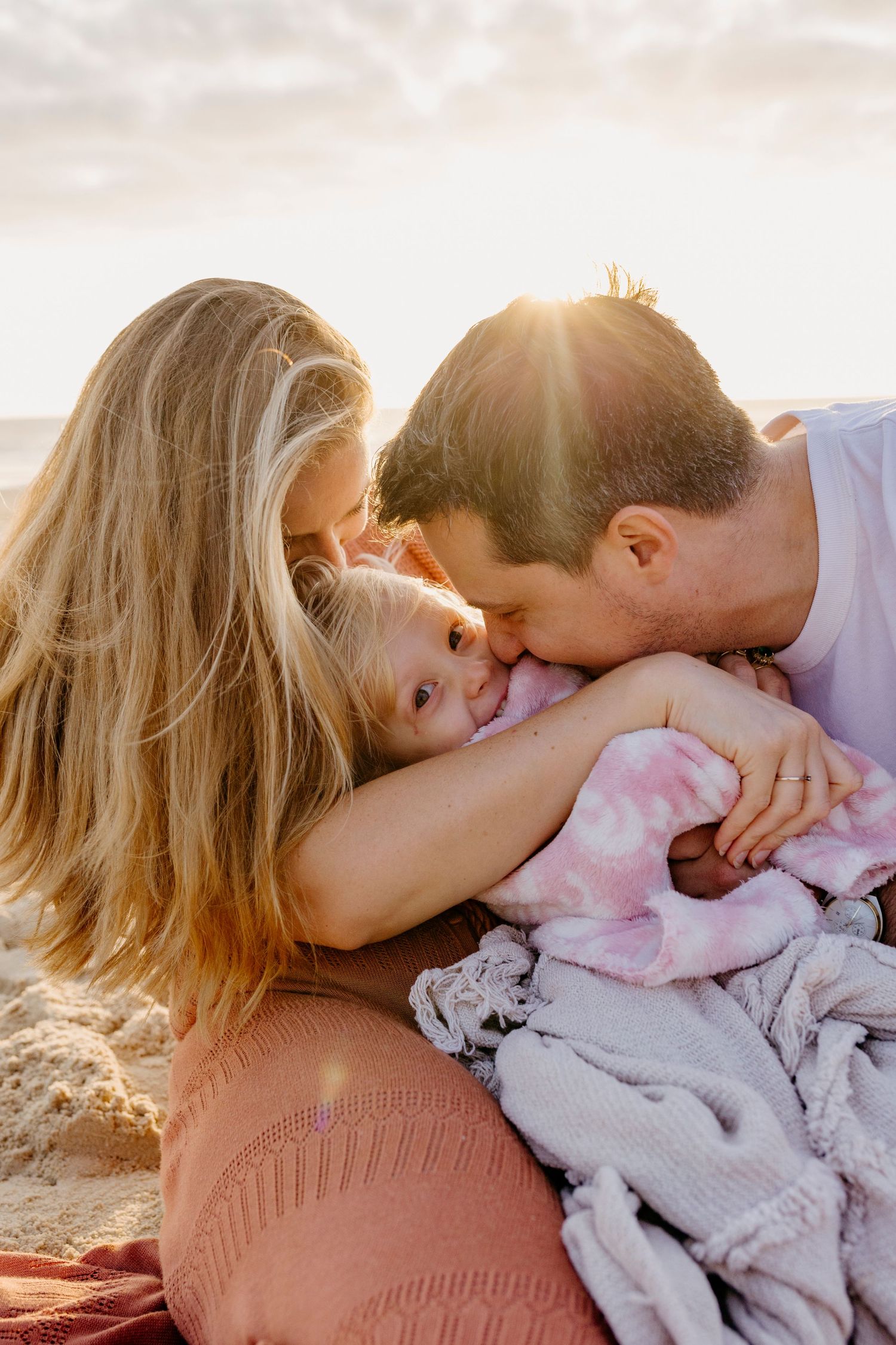 A tender moment captured between a couple lying together on a blanket at sunset.