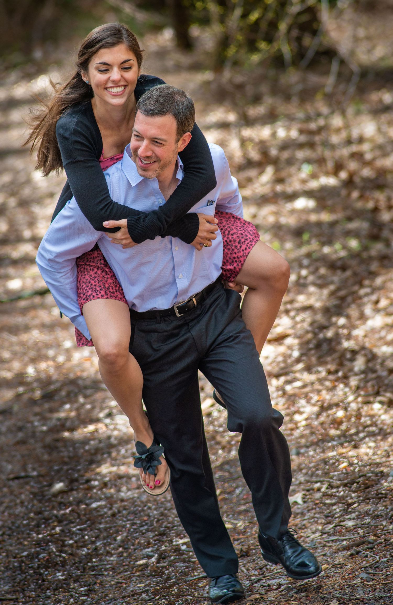 A couple shares a playful piggyback ride moment on an outdoor trail.