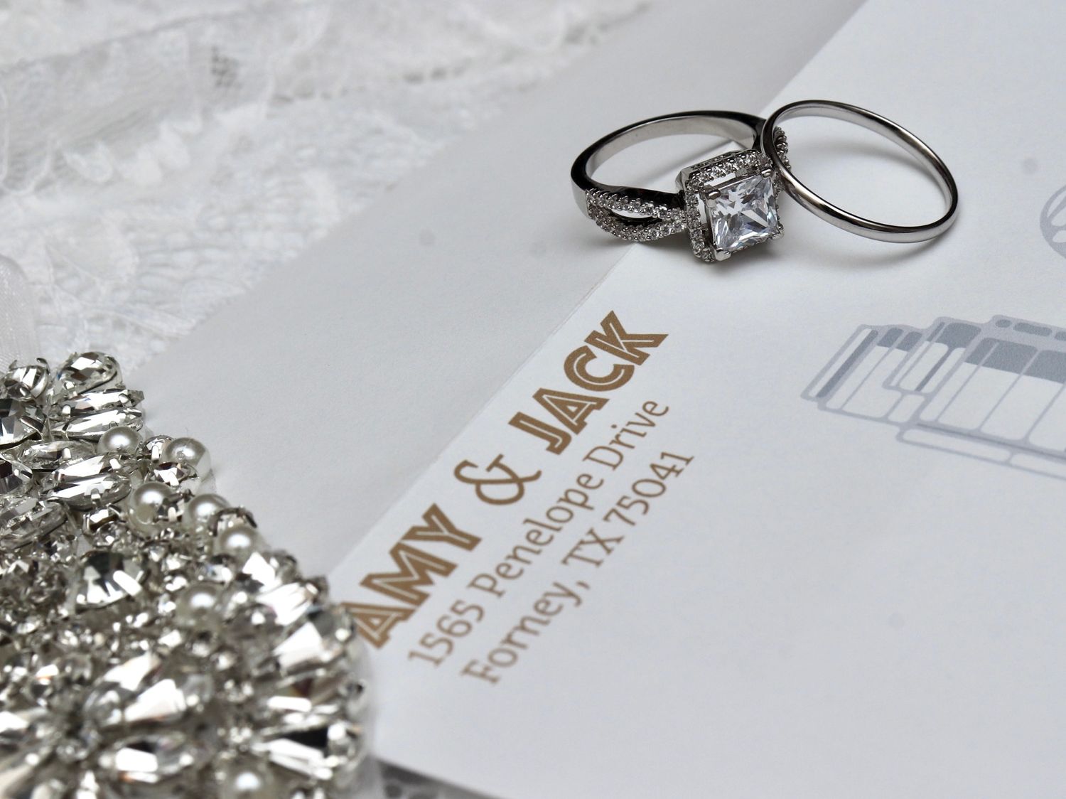 Wedding rings and jewelry displayed on elegant white stationery.