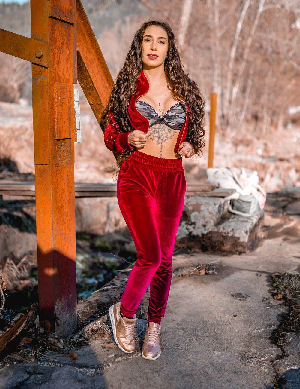 Stylish red velvet ensemble captured against wooden architectural elements in natural lighting.