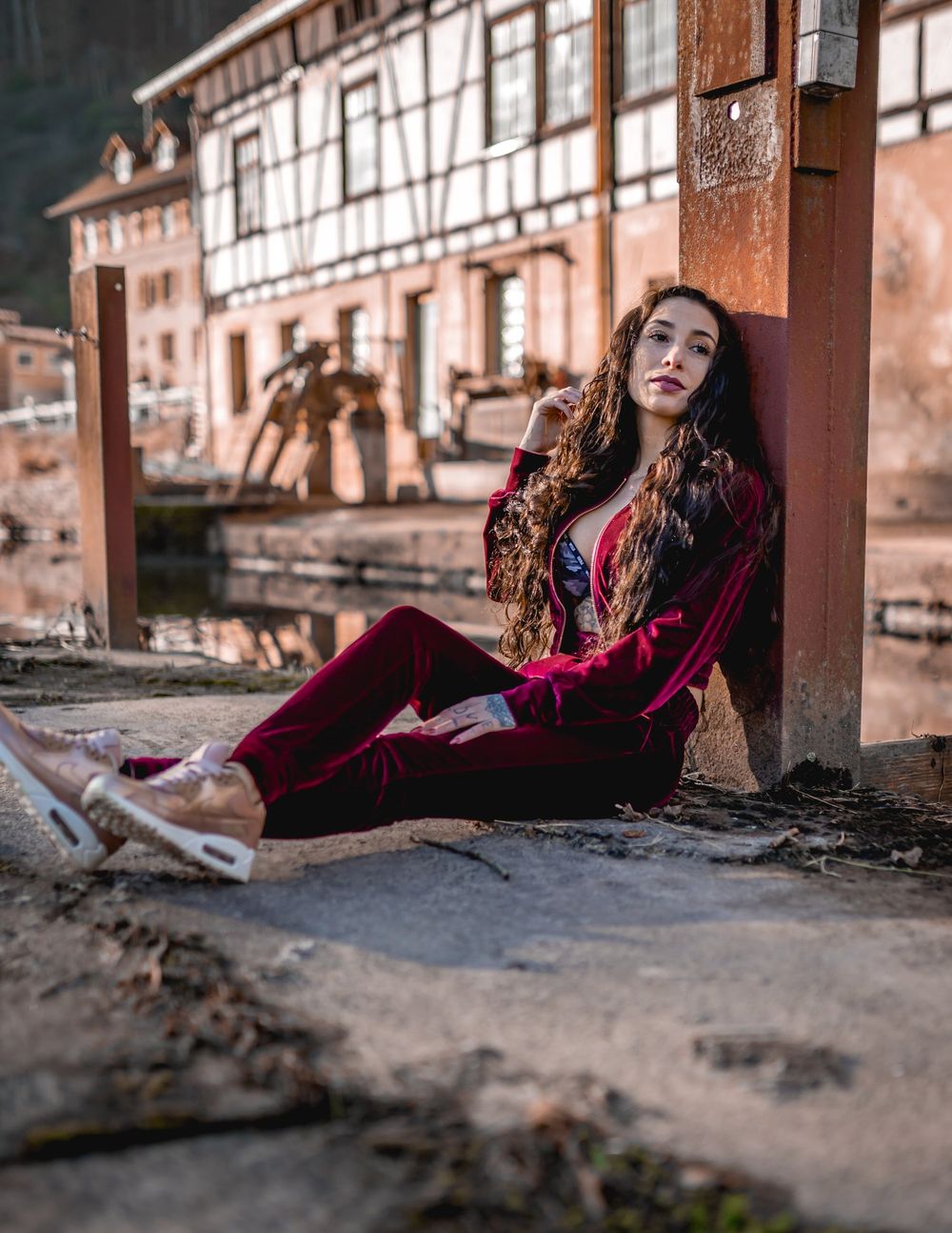 Moody portrait against vintage half-timbered buildings in warm autumn tones.
