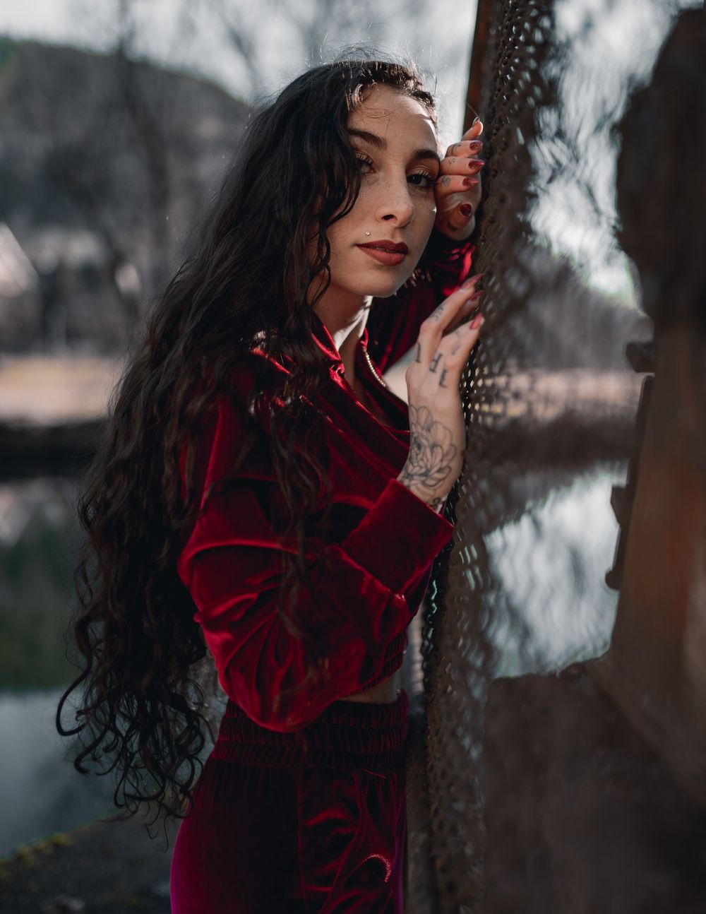Vintage-inspired portrait in red velvet against moody natural background.