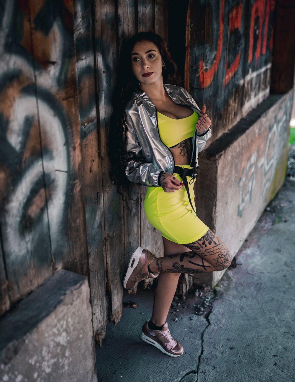 Urban fashion shoot featuring metallic jacket and bright yellow dress against graffiti backdrop.