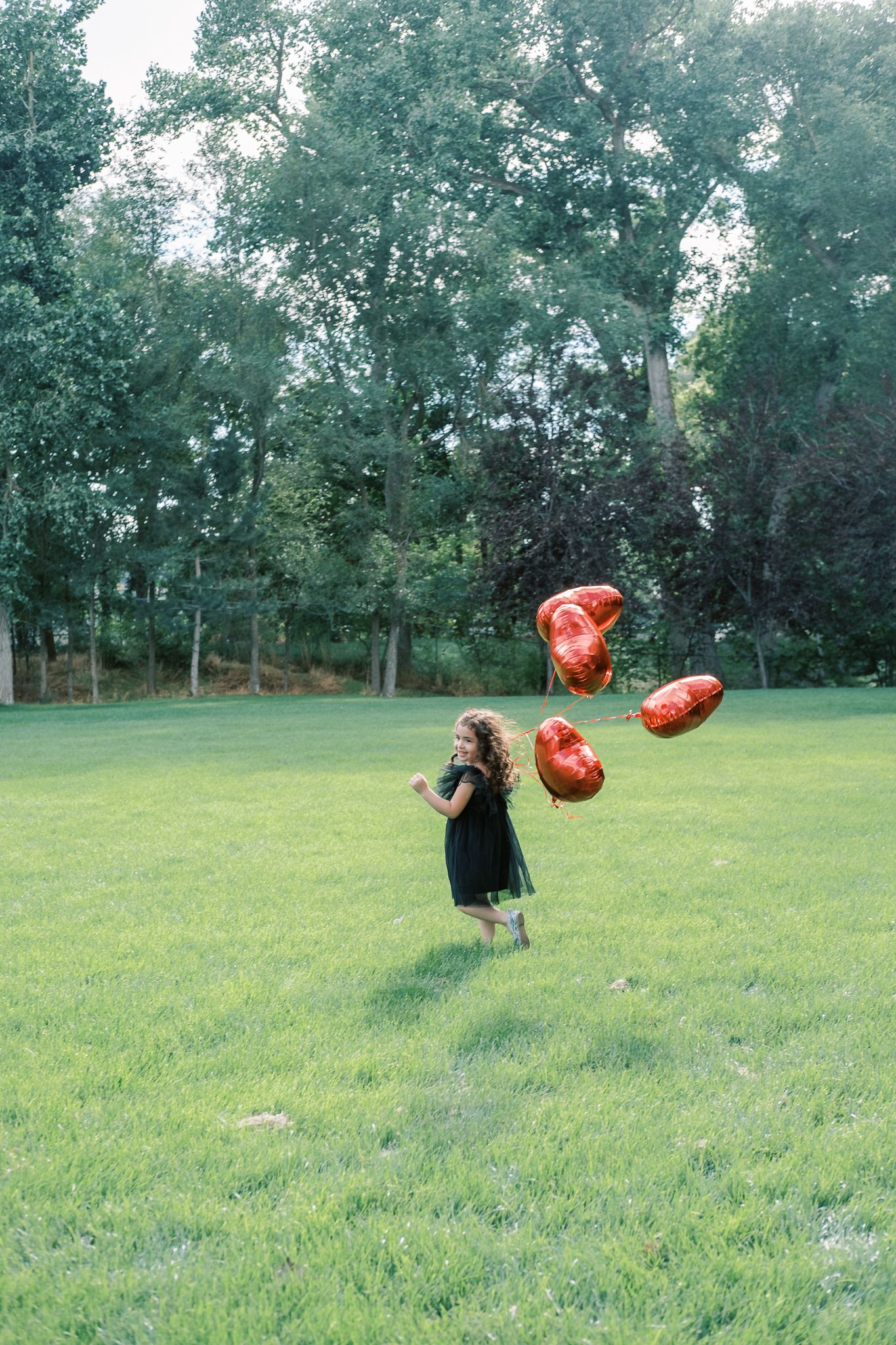 at woodland park a 4 year-old runs with her balloons in Farmington, utah.