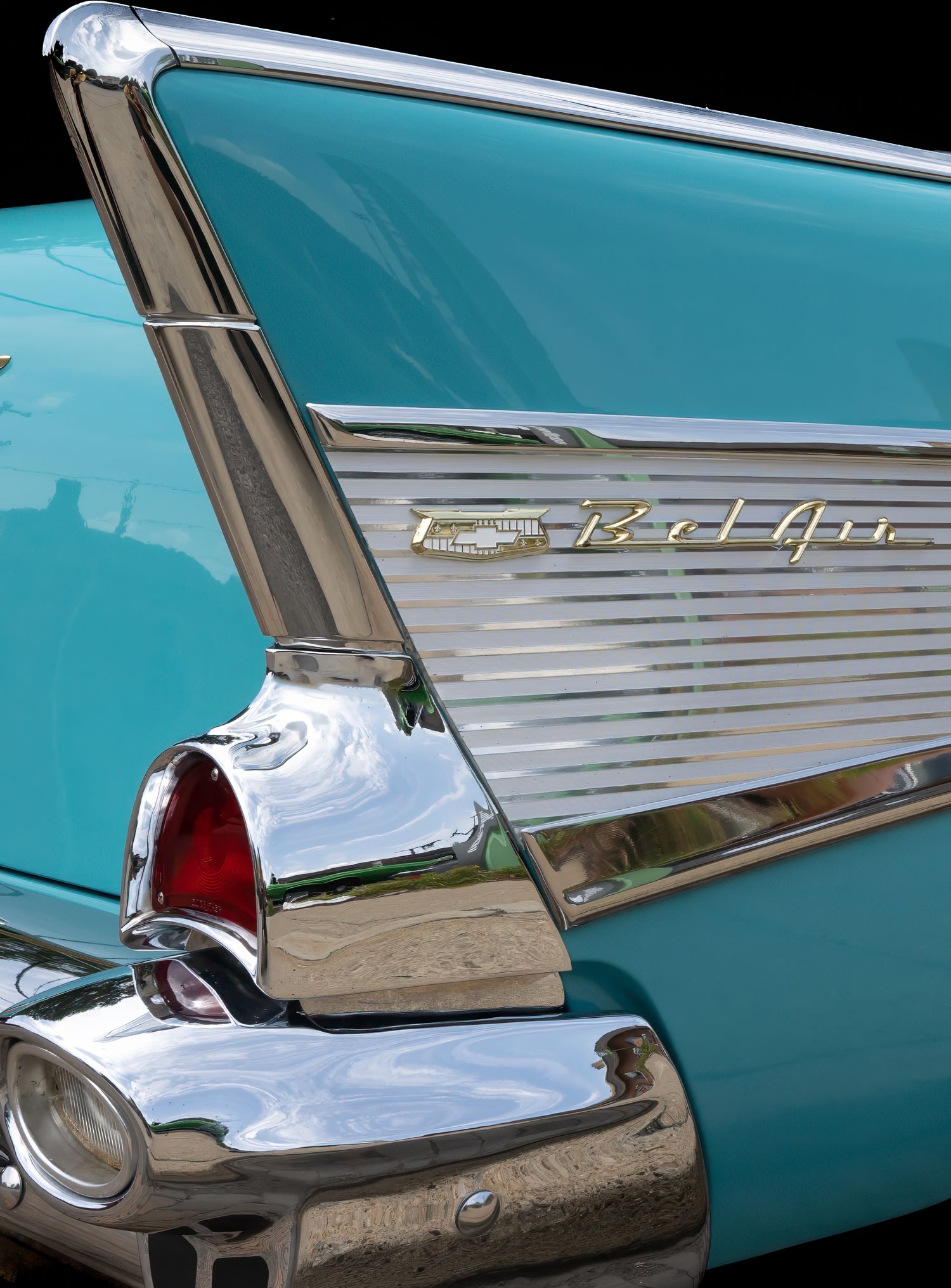Chrome trim and fins detail of a classic 1950s Chevrolet Bel Air in turquoise.