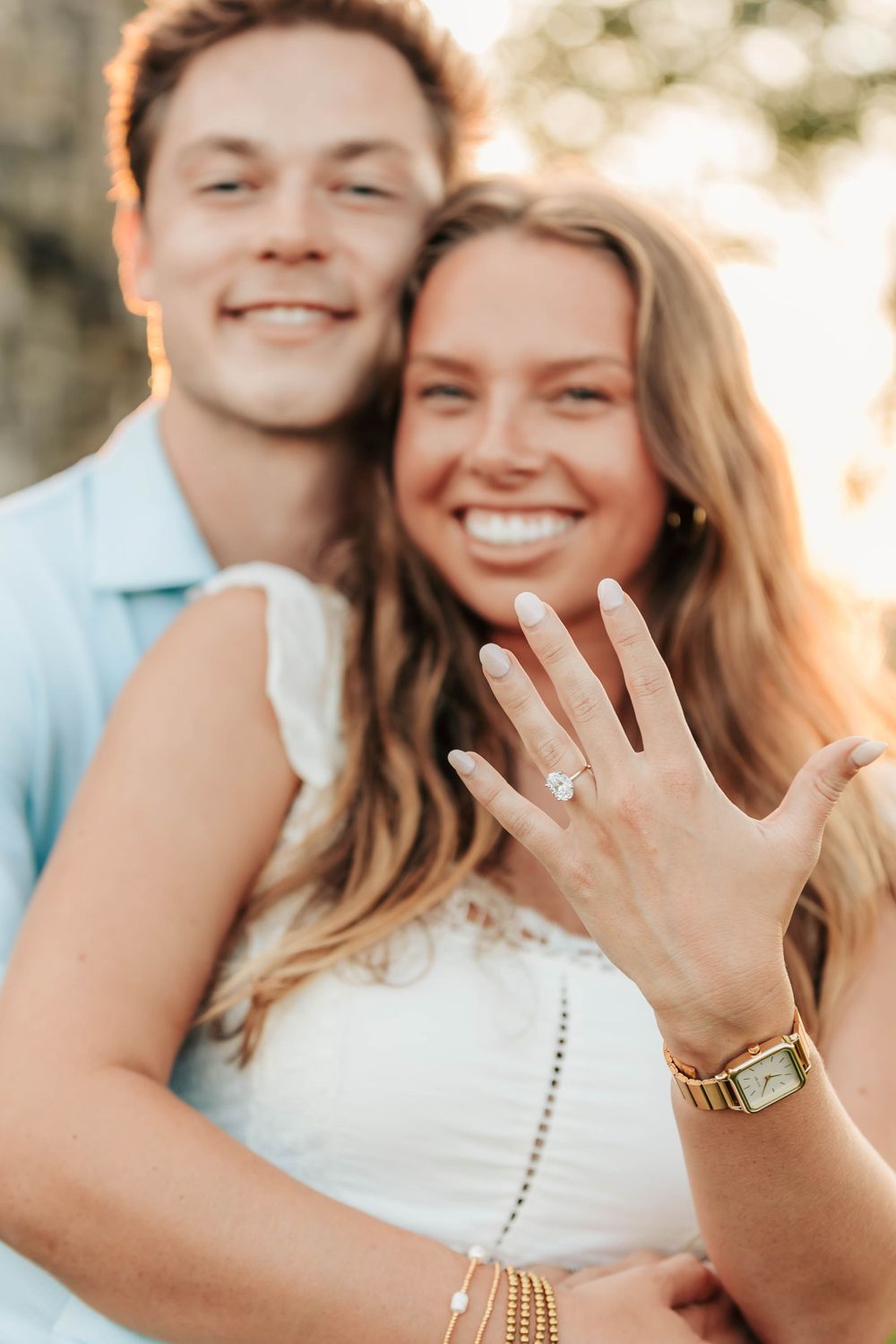 Someone showing off their new engagement ring with a sparkly diamond in golden sunlight.