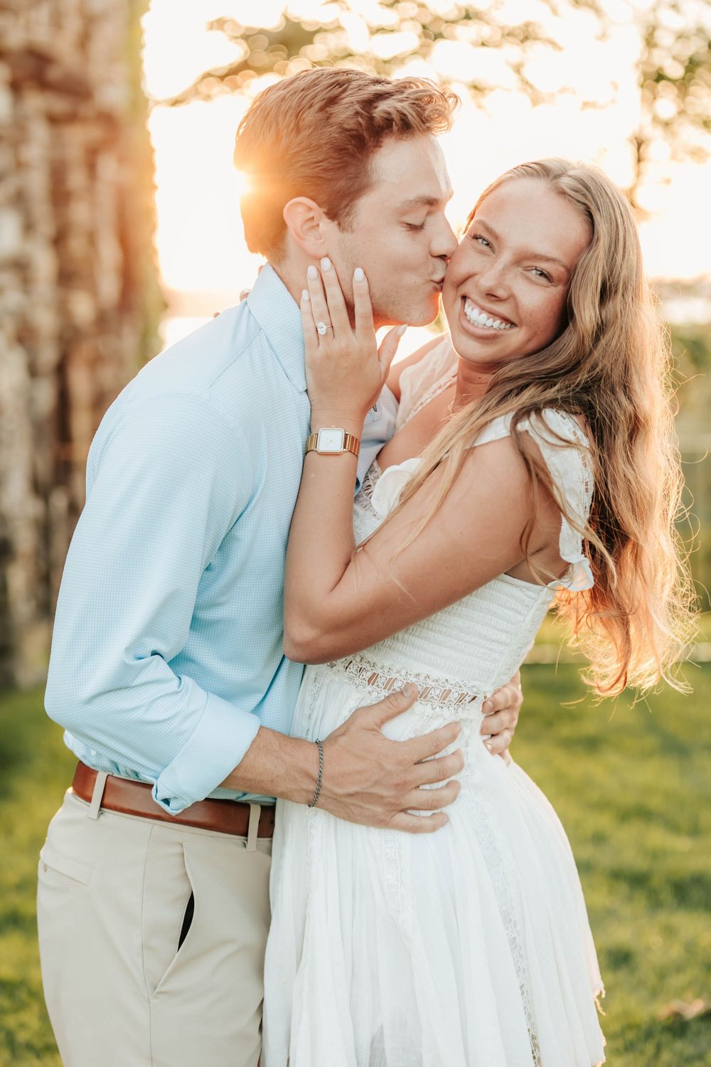 A romantic engagement photo showing an intimate moment between a couple at sunset.