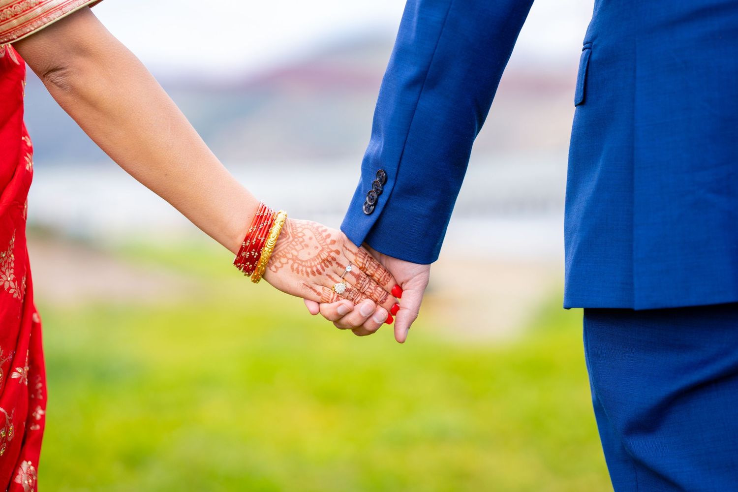 Close-up of decorated hands holding during outdoor wedding photoshoot.