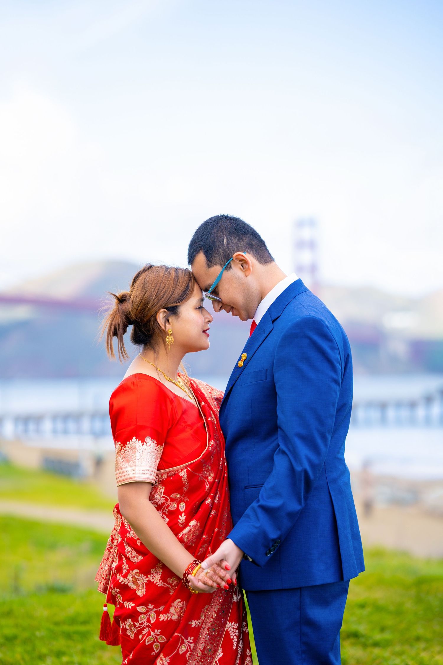 A romantic couple poses in traditional and formal attire with the Golden Gate Bridge in the background.