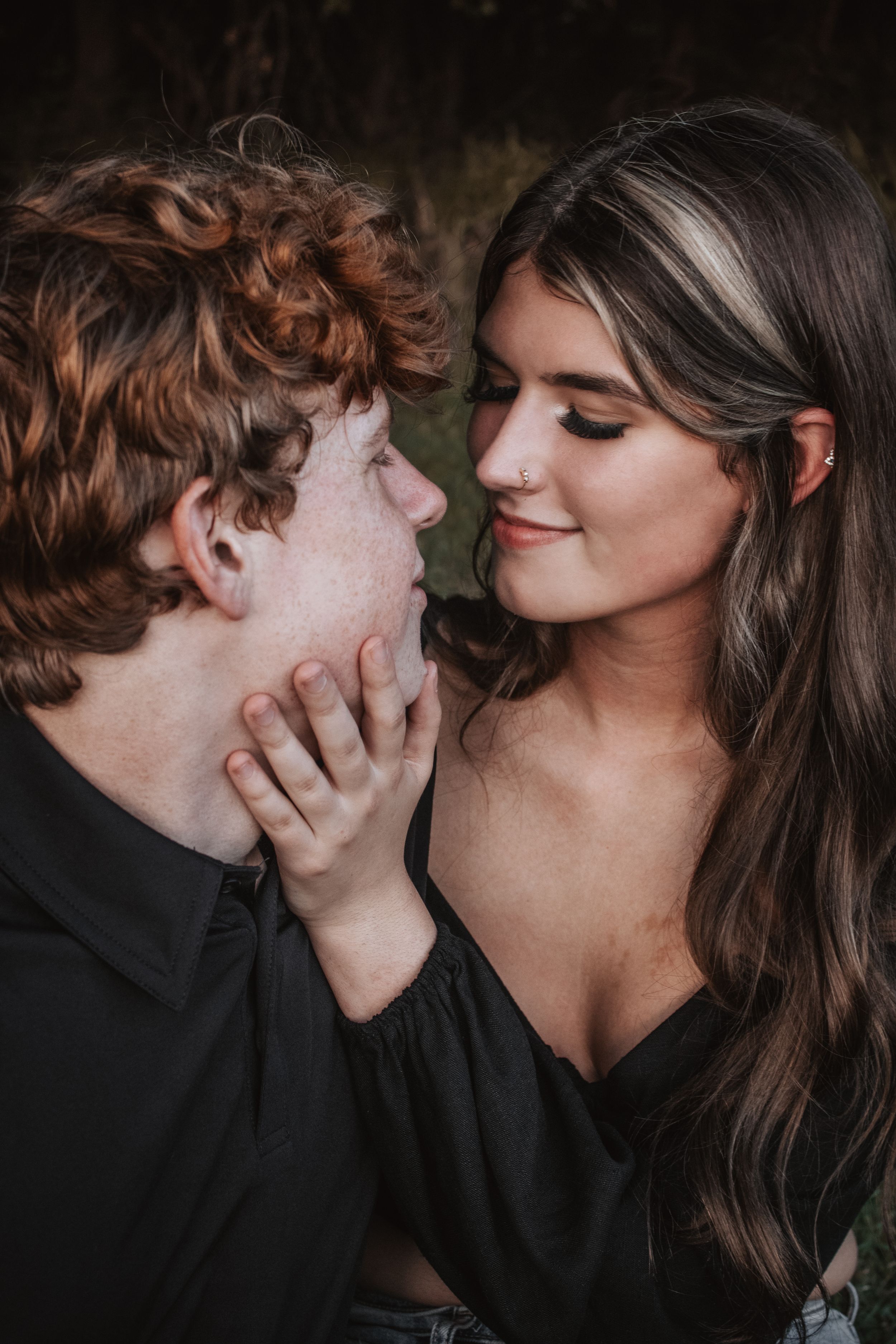 Intimate couple sharing tender romantic moments in a dark setting with dramatic lighting.