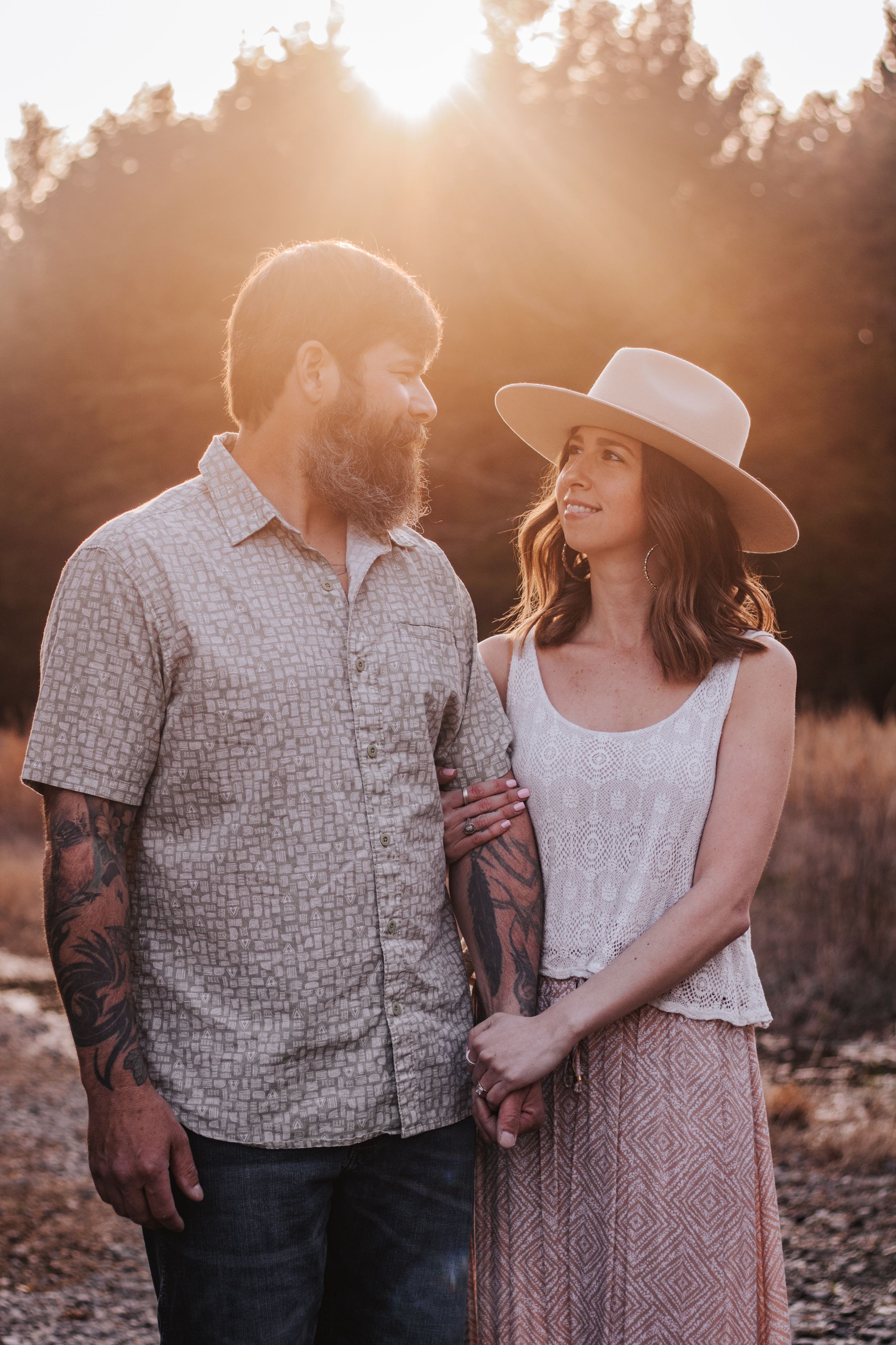 Sunset engagement photos with couple in western wear against desert backdrop.
