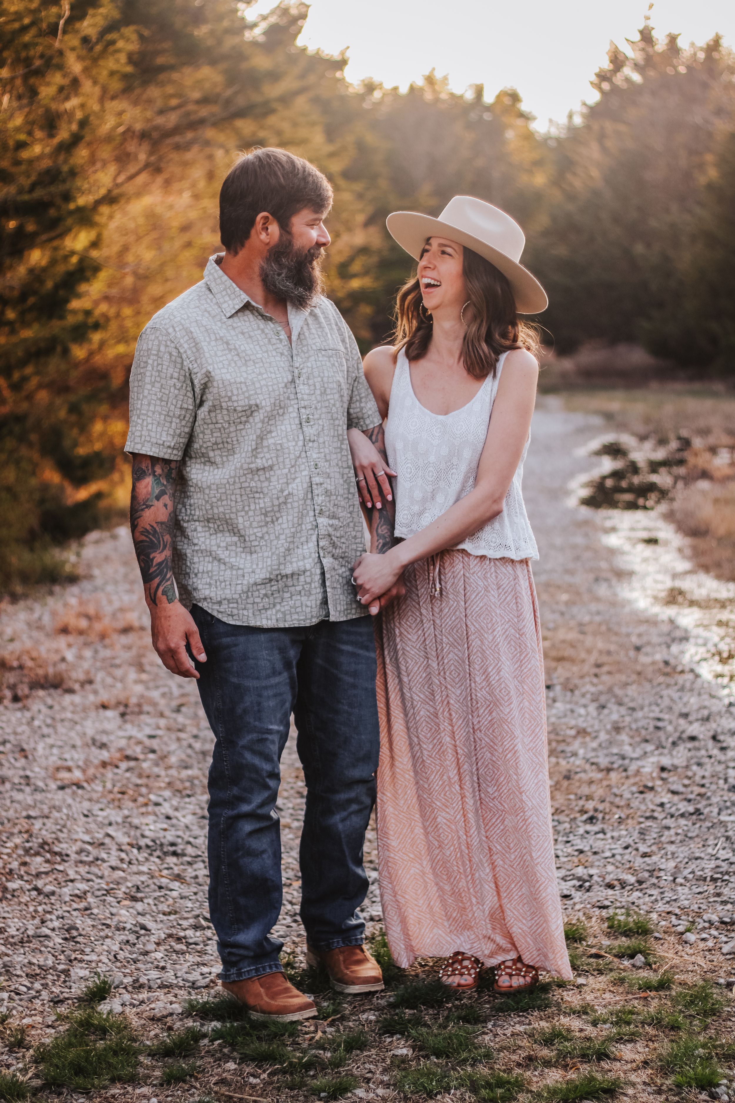 Couple in casual western attire walking together during golden hour on a rocky path.