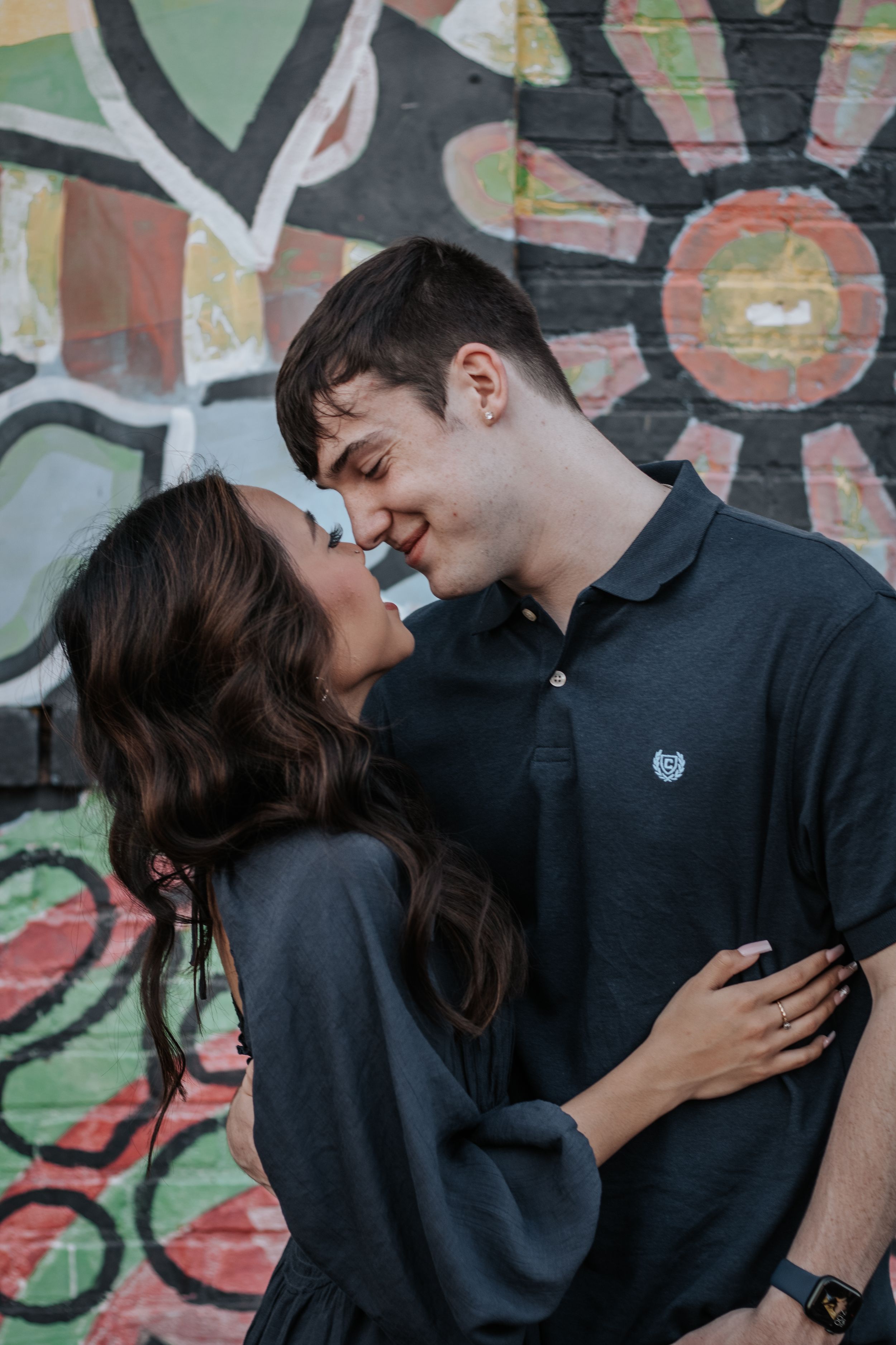 Couple sharing intimate moments against colorful graffiti wall background.