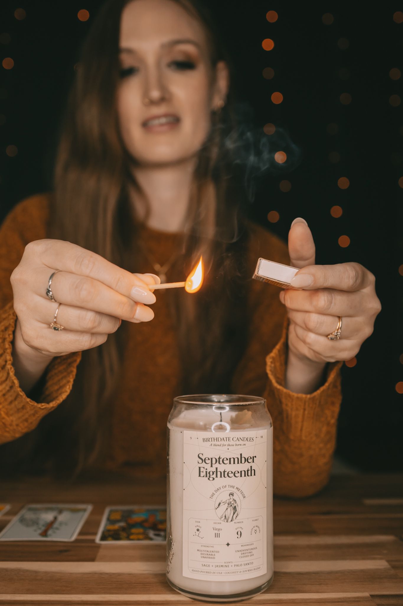 A woman holds a lit match over a candle