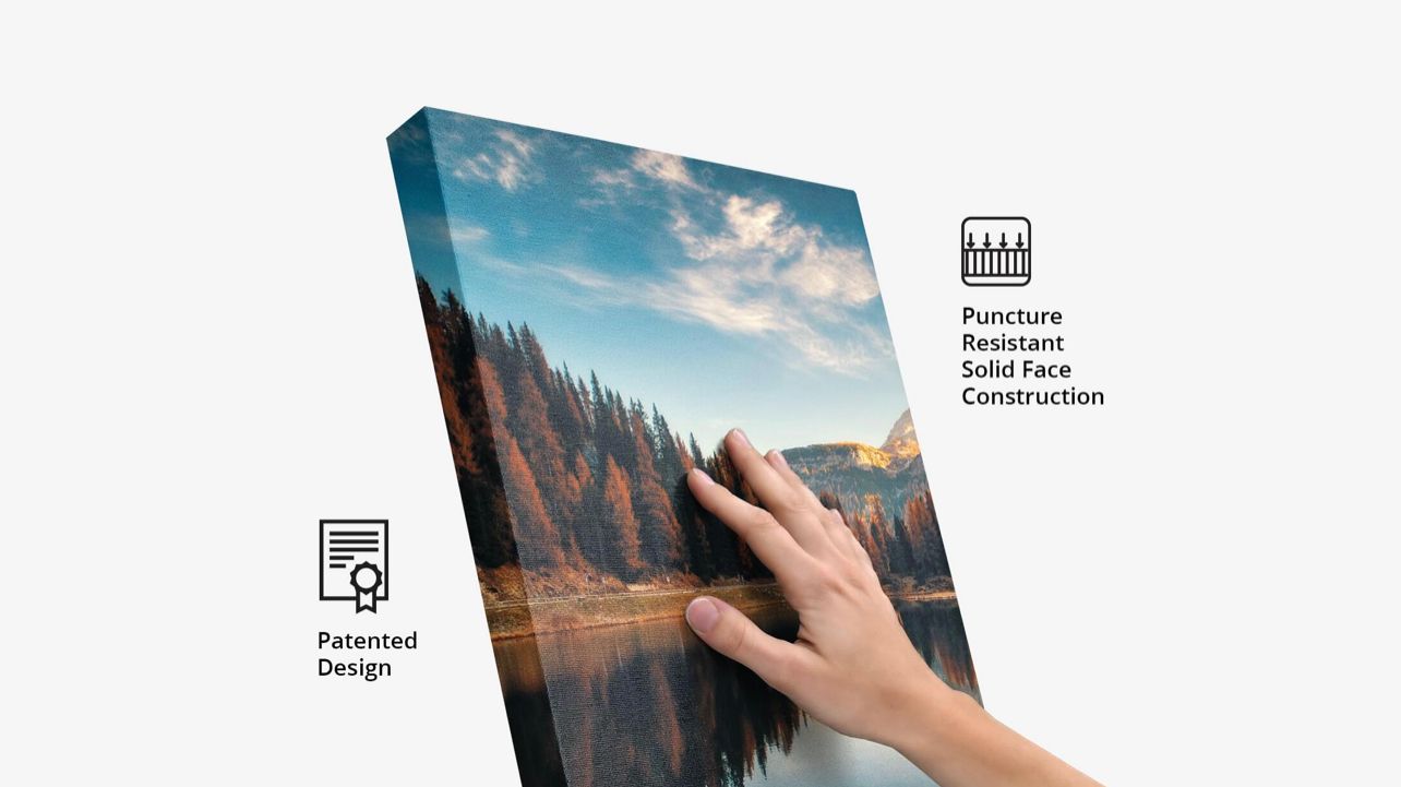 Hand pressing on a canvas print showing a mountain lake autumn scene with puncture-resistant construction.