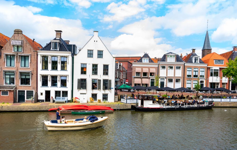 Traditional Dutch architecture along a canal with boats and church spire in Amsterdam.