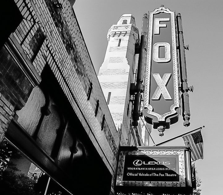 Black and white low angle view of vintage Fox theater sign on brick building facade.