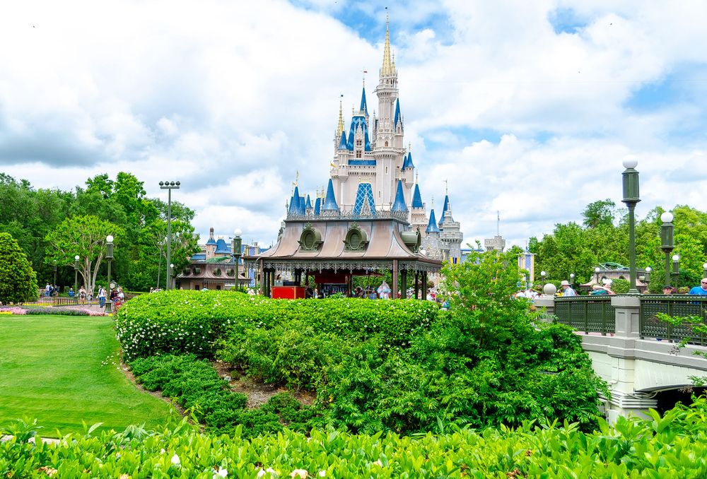 Iconic Disney castle with manicured gardens and pathways on a sunny day.
