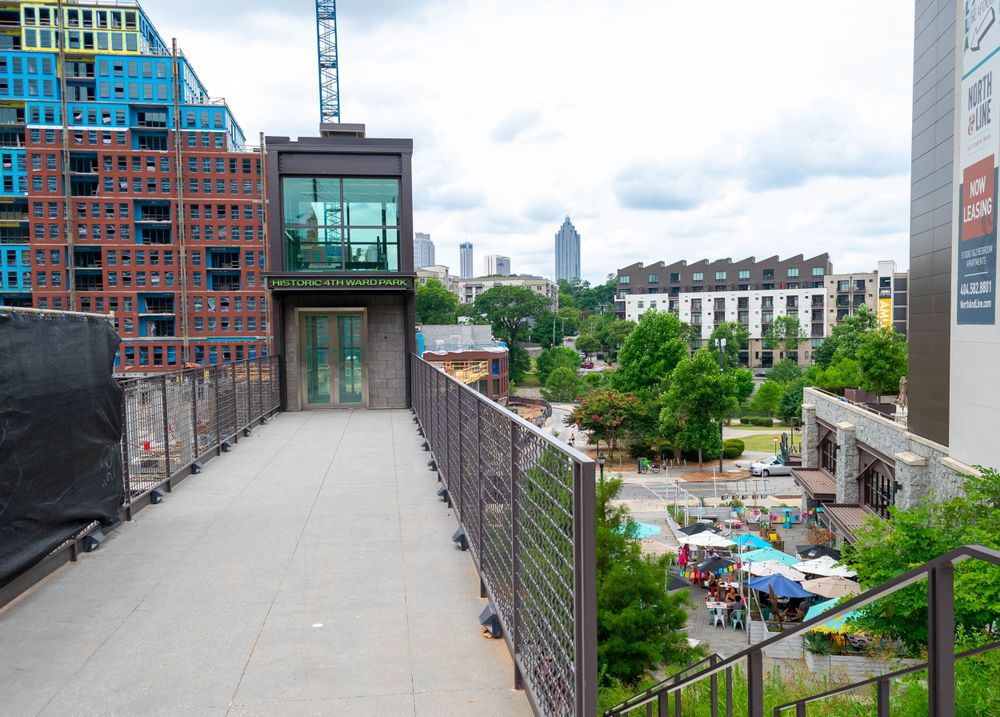 Modern urban walkway with glass building and city skyline view.
