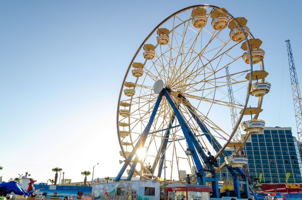 Large ferris wheel against blue sky at beachfront amusement park.
