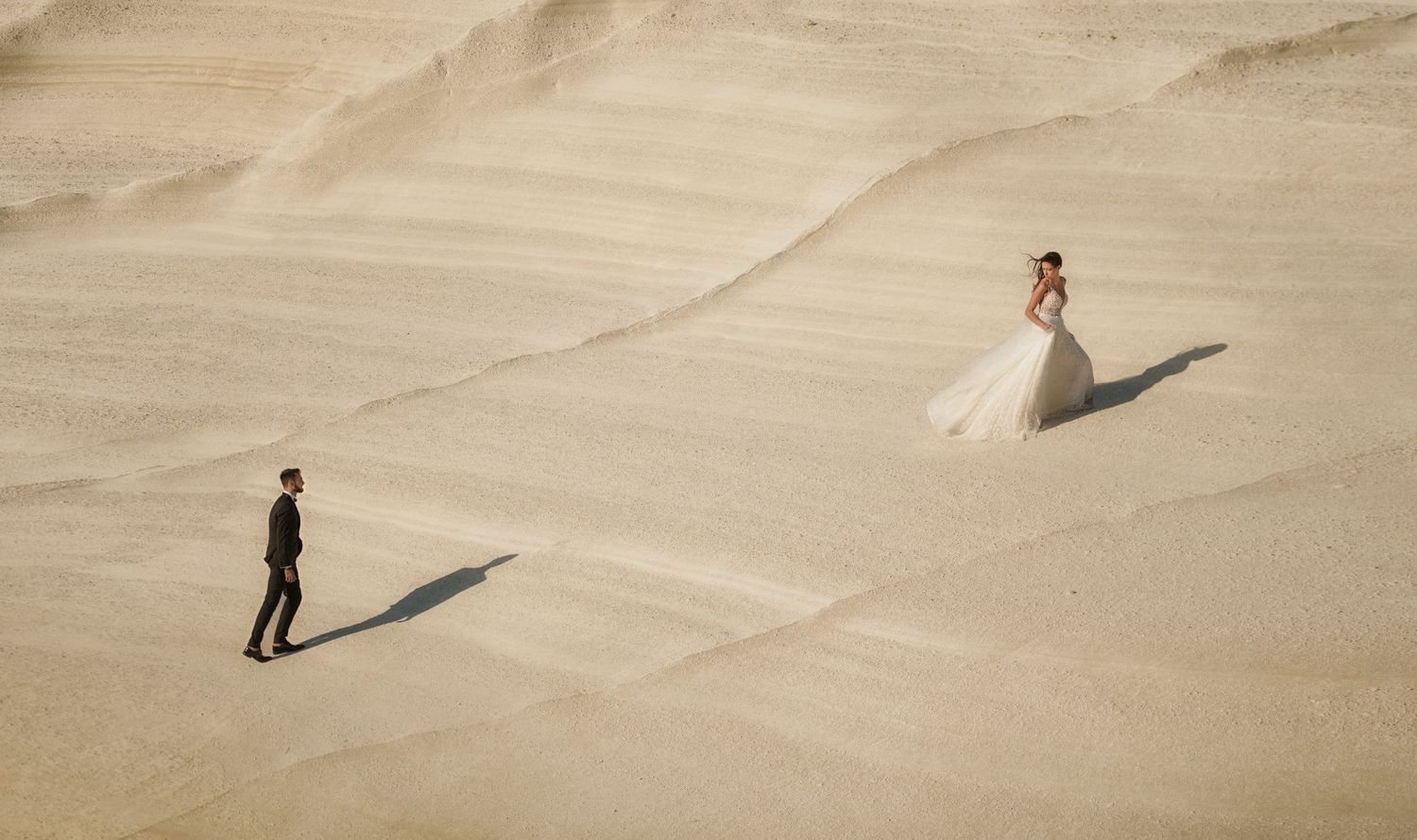 Minimalist desert landscape with long shadows cast on sandy dunes.