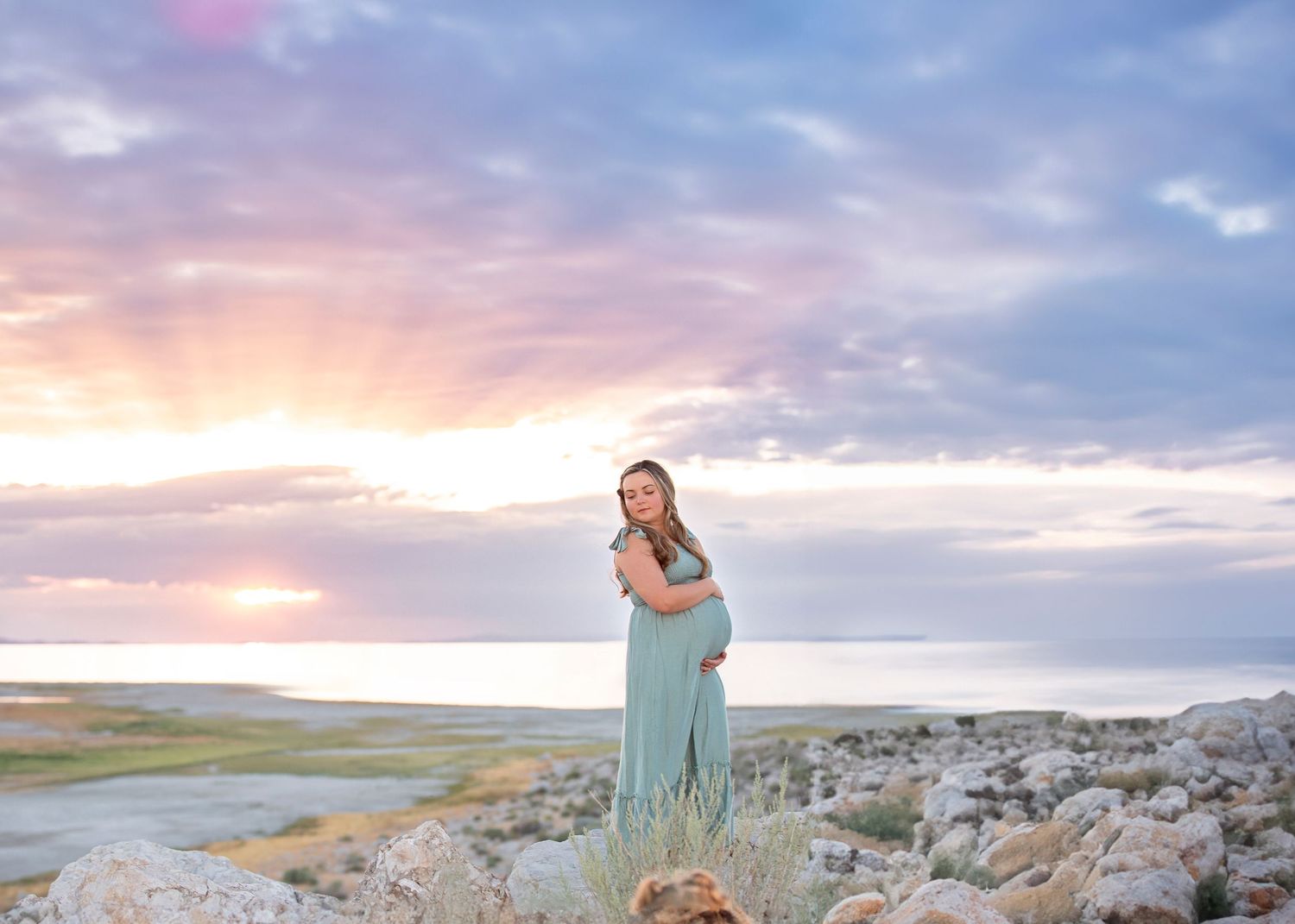 maternity photoshoot at antelope island woman holding pregnant belly at sunset