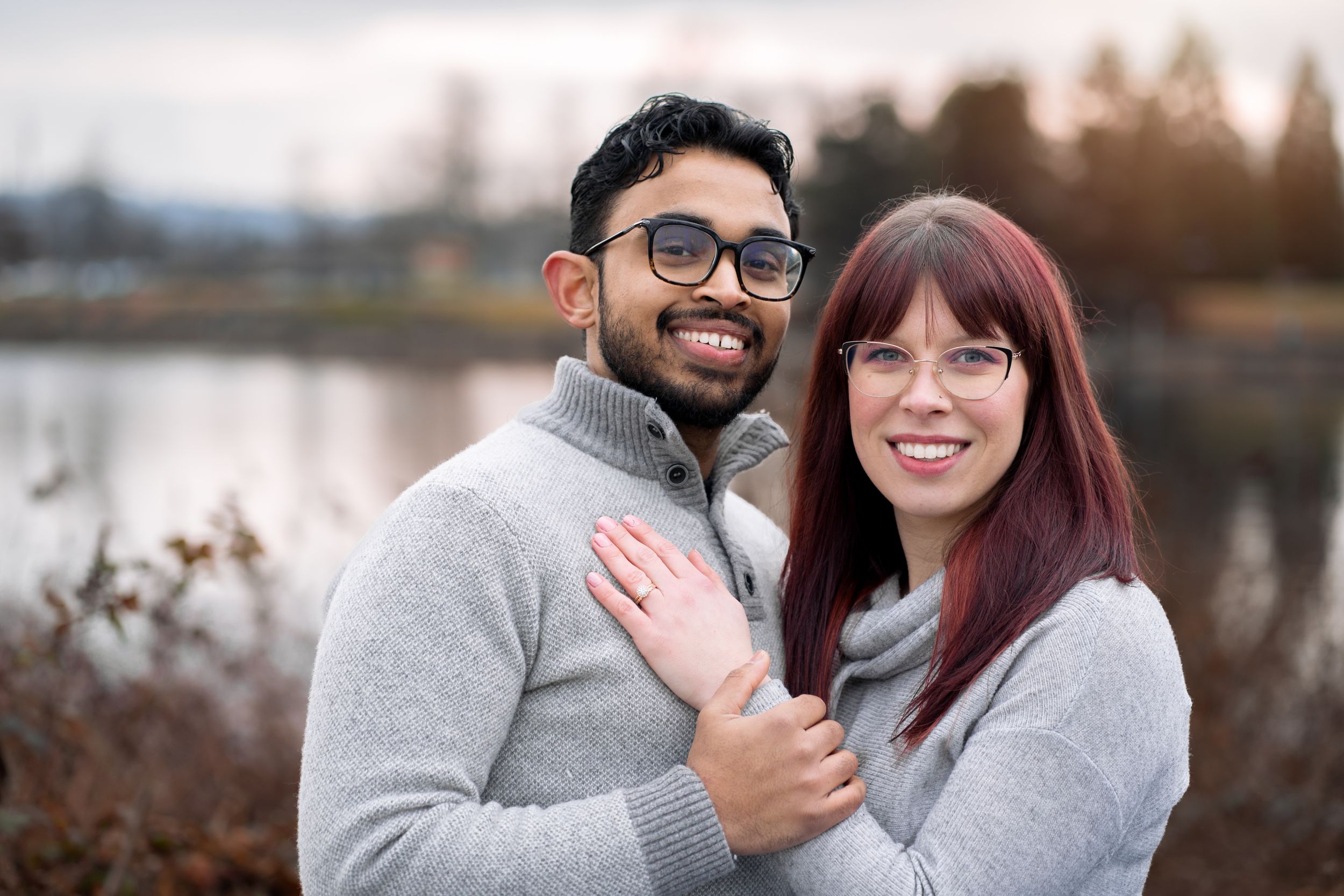 Happy couple sharing playful moments outdoors wearing coordinated gray and red outfits.