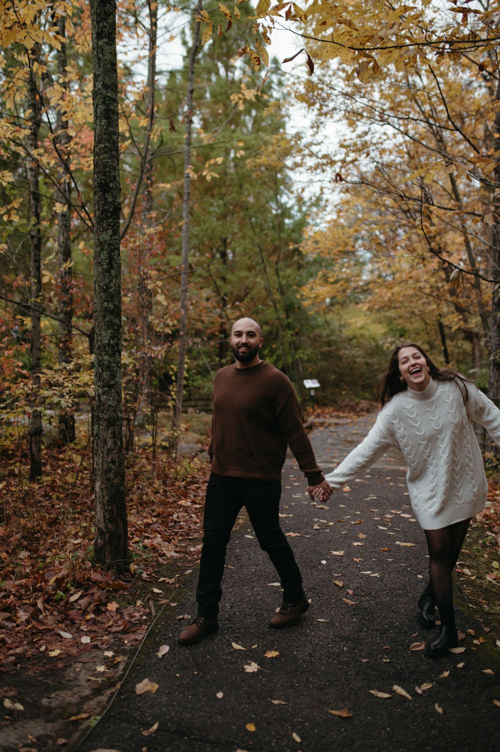 Couple enjoying an autumn walk on a forest path surrounded by golden leaves.