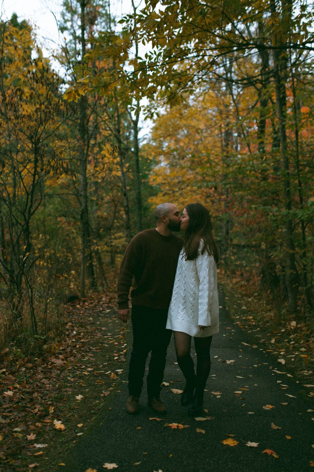 A romantic moment captured on a forest path during fall season.