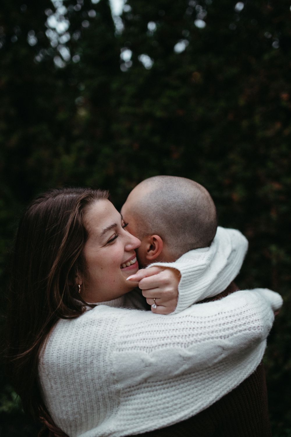 A romantic embrace captured in black and white against a natural outdoor backdrop.