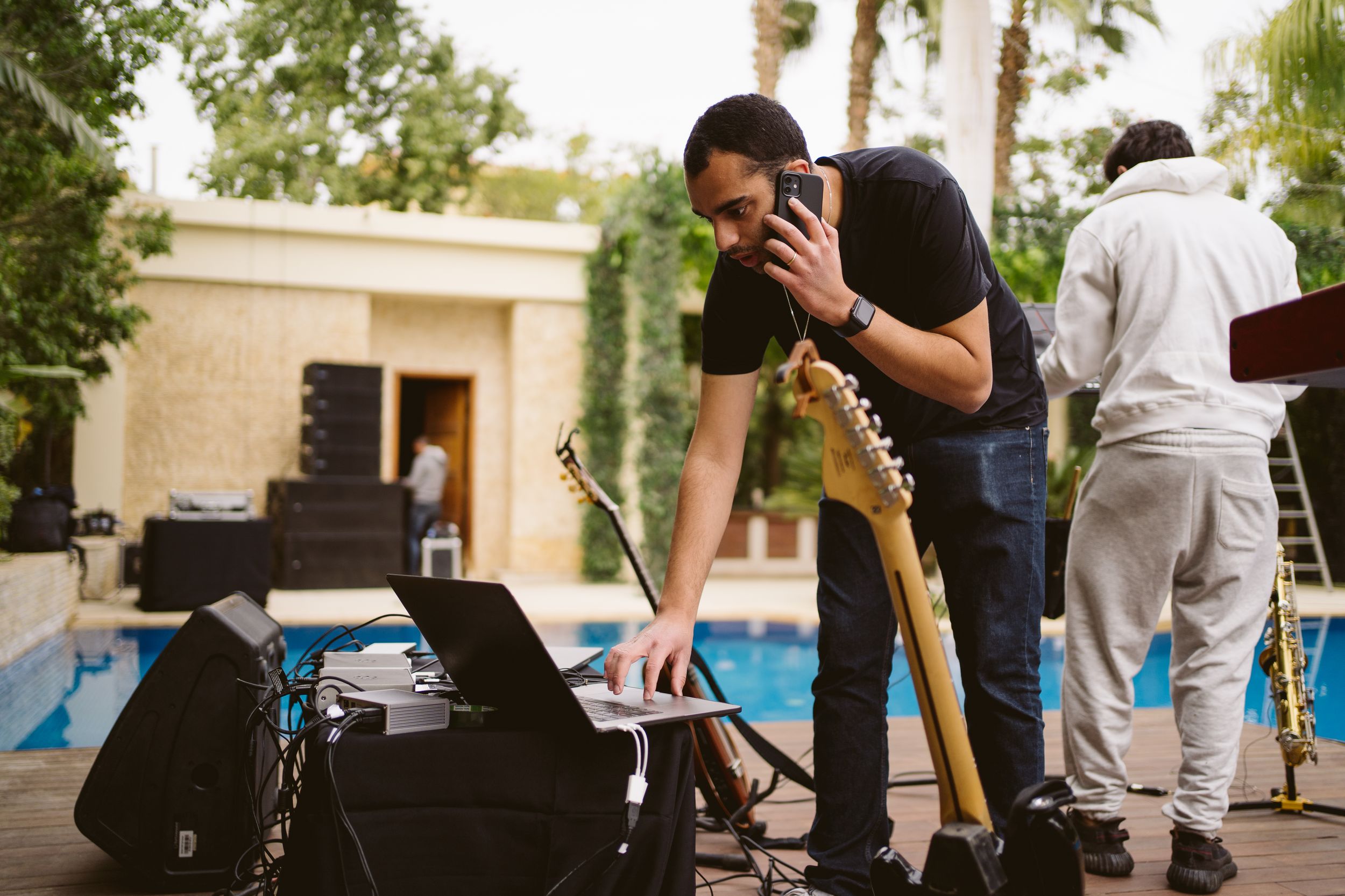 Photographer works with equipment near poolside during outdoor shoot setup.