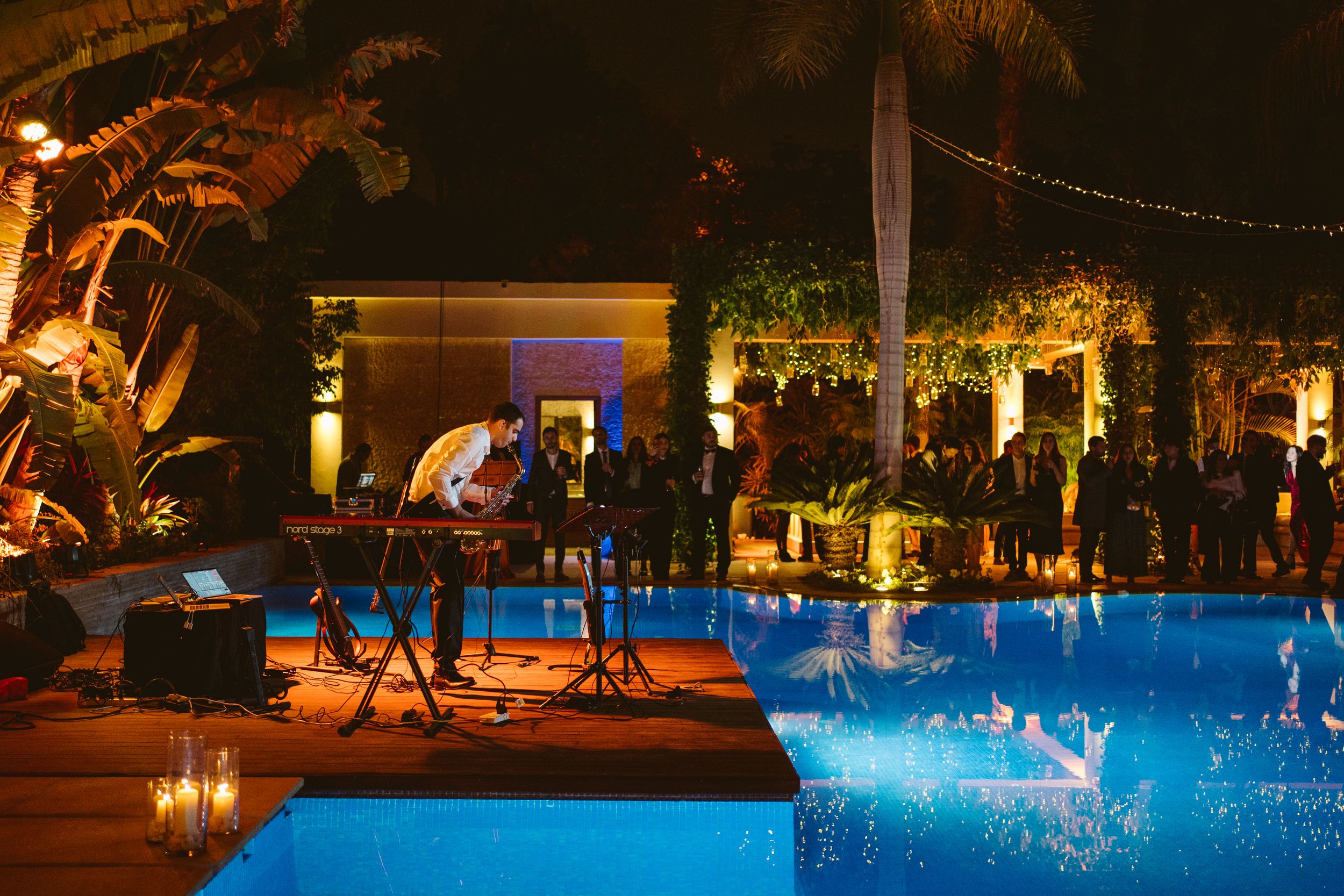 Nighttime pool party setup with stage equipment and ambient lighting creating a festive atmosphere.