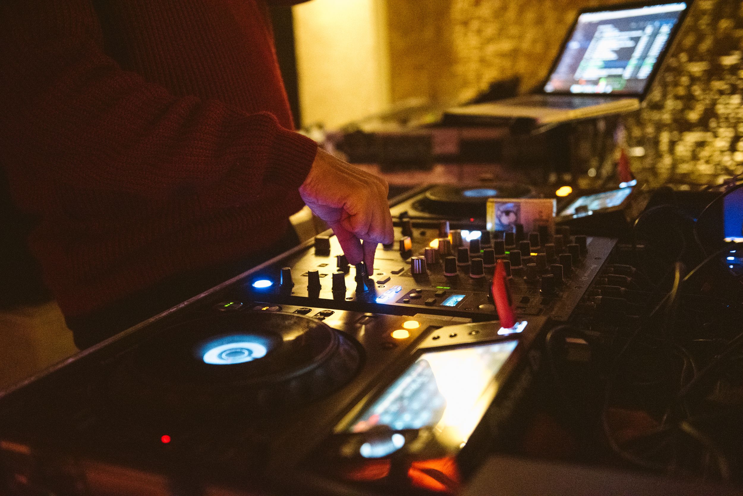 Close-up shot of DJ equipment and controls in a dark nightclub setting.