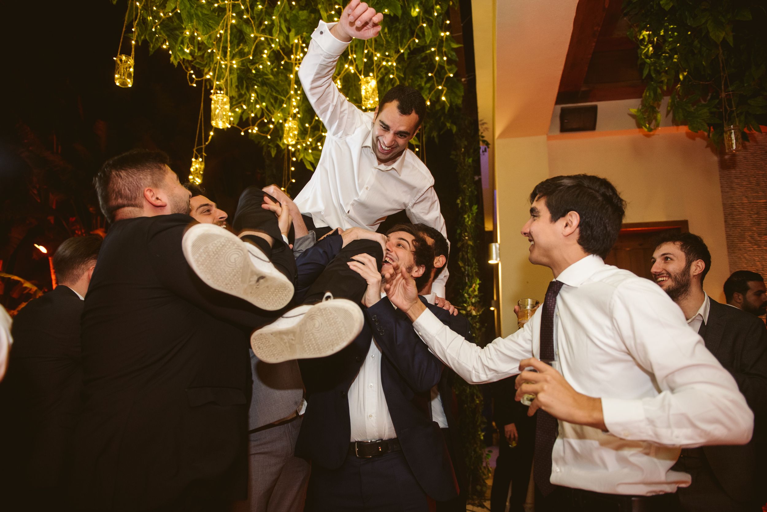 Energetic wedding guests lifting and celebrating during a festive reception.