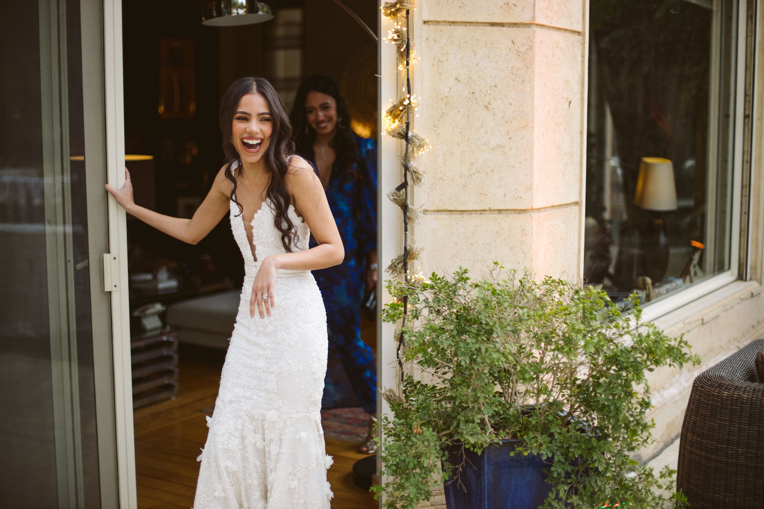 A white lace wedding dress shown in natural light against a Mediterranean style building entrance.