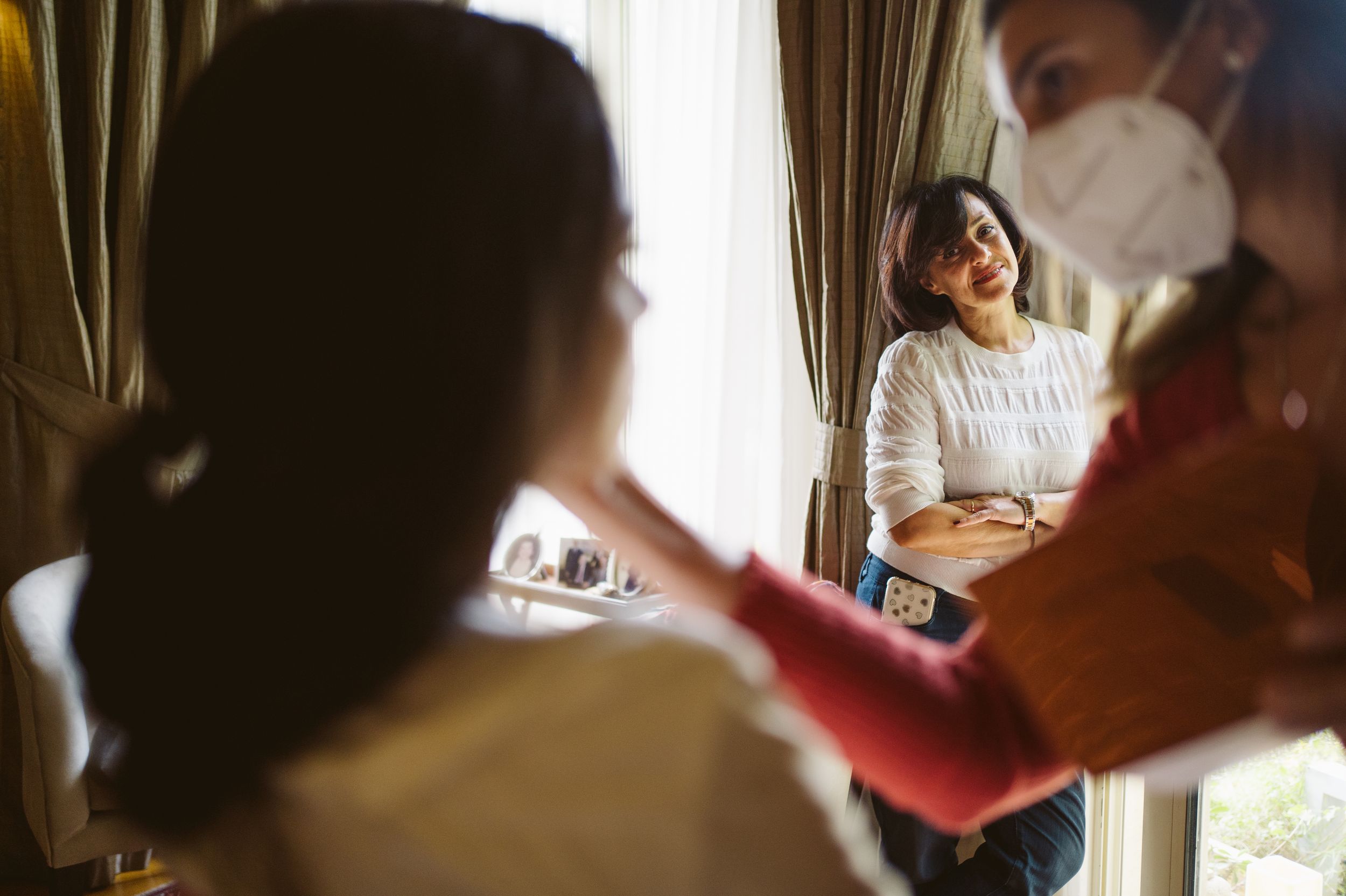 Person getting hair and makeup done in a warmly lit room with curtains.