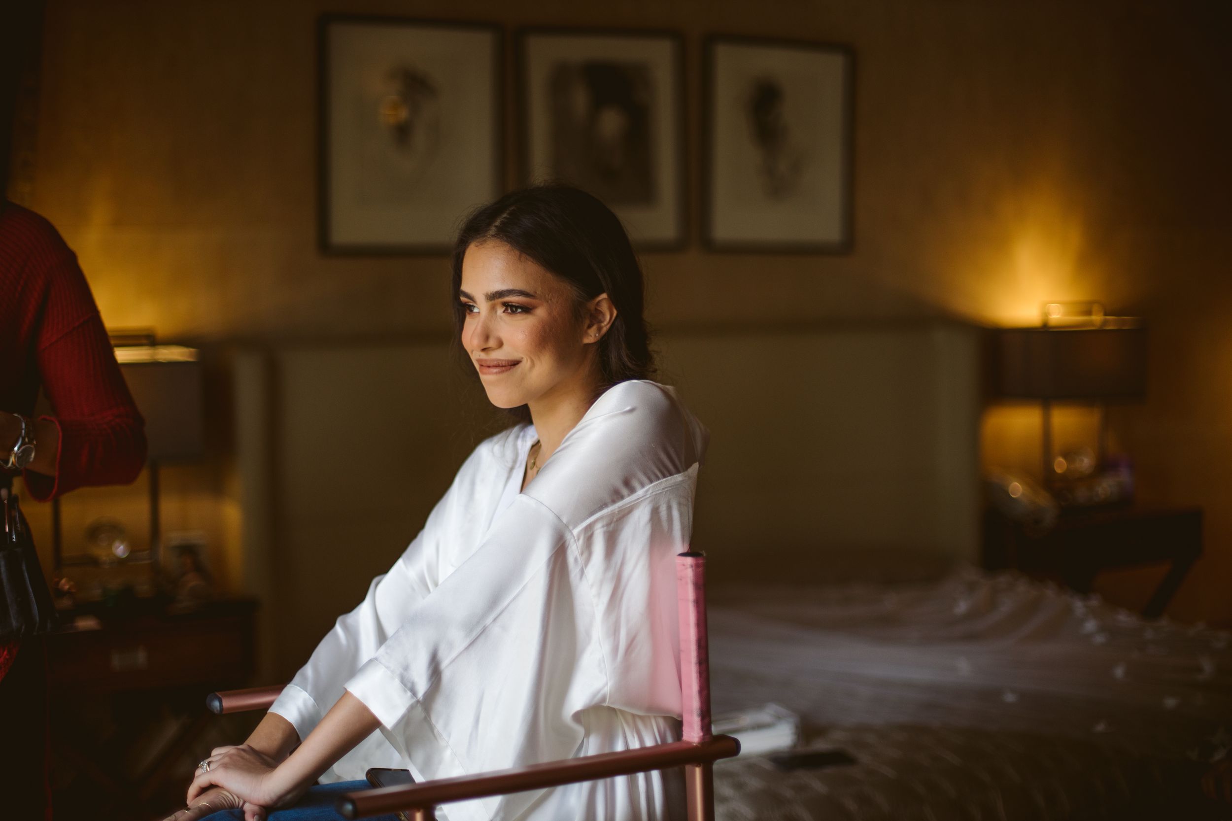 Person in white robe smiling during wedding day preparations.
