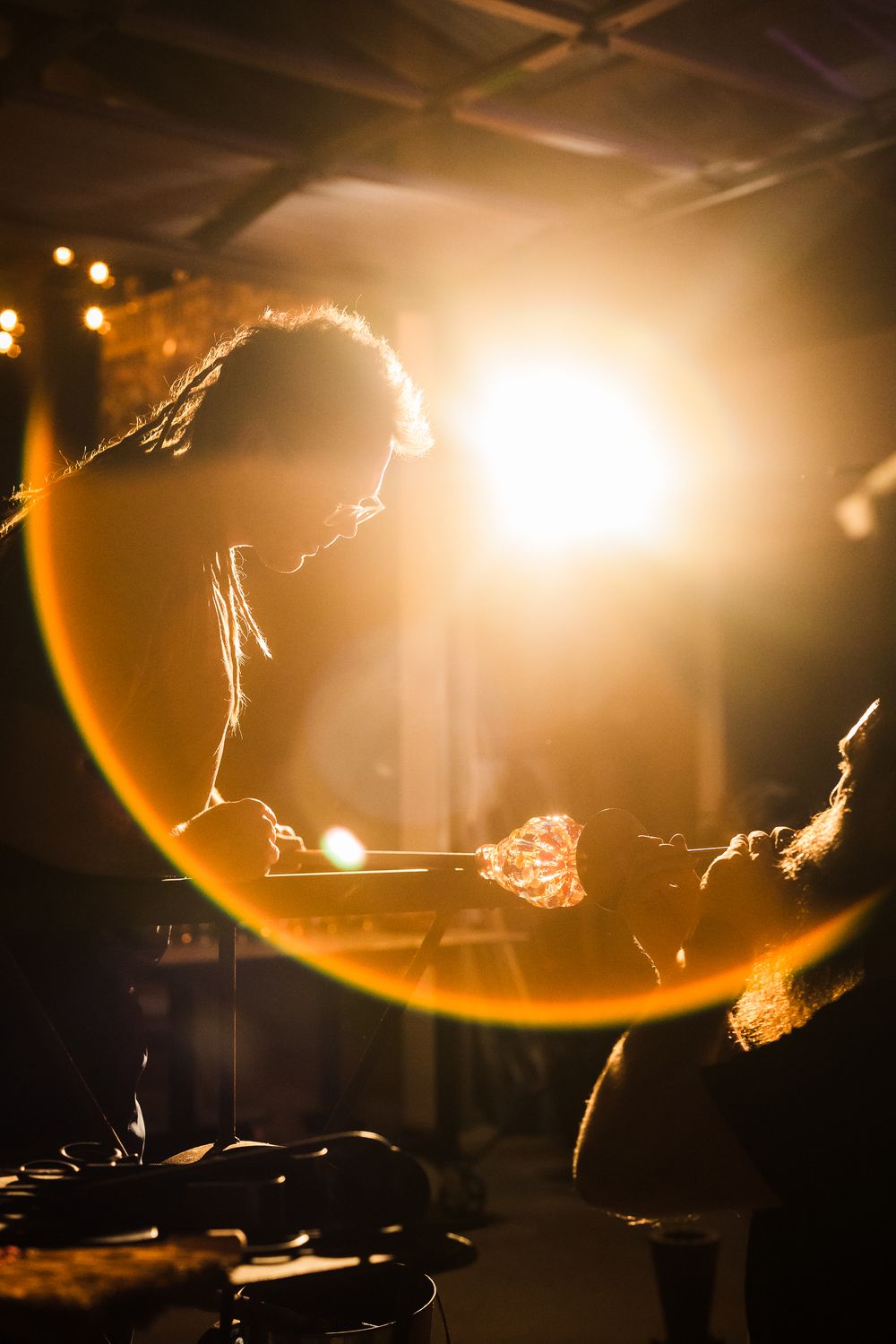 Silhouetted figures performing with fire against warm backlit stage lighting.