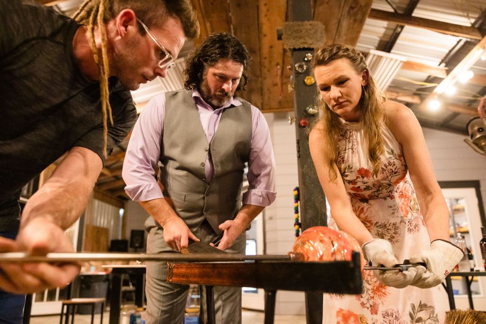 Group of people engaged in a hands-on cooking or craft activity at a wooden table.