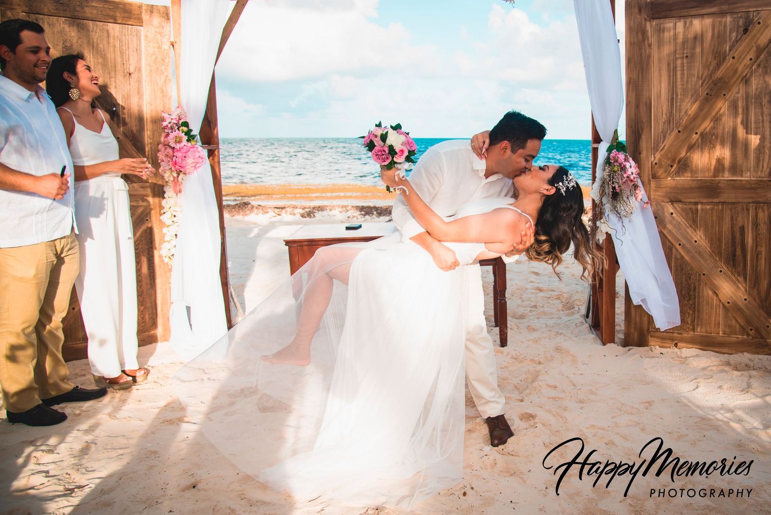 Beautiful beach wedding ceremony setup with wooden doors and floral arrangements along sandy pathway.