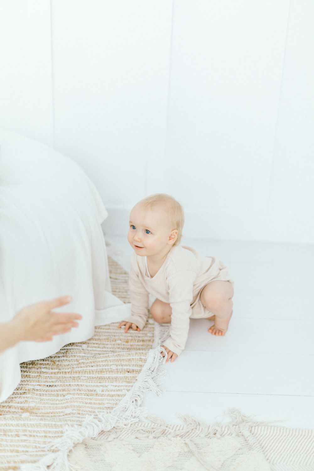 Baby crawling on textured rug in bright white room.