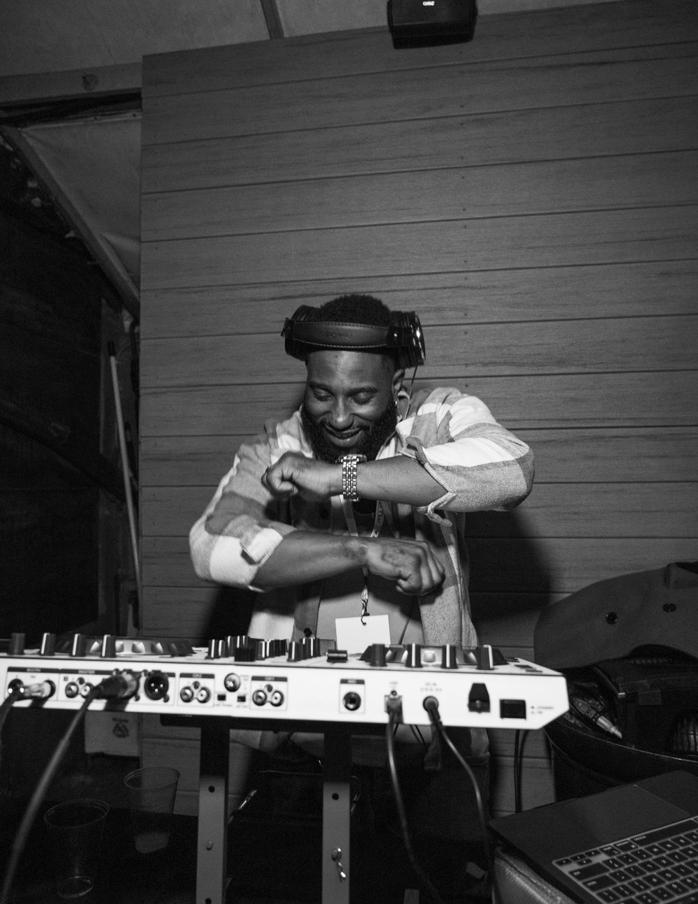 DJ performing on electronic music equipment in black and white photo.