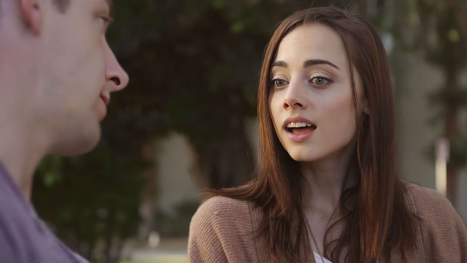 Two people having an animated conversation outdoors at dusk.