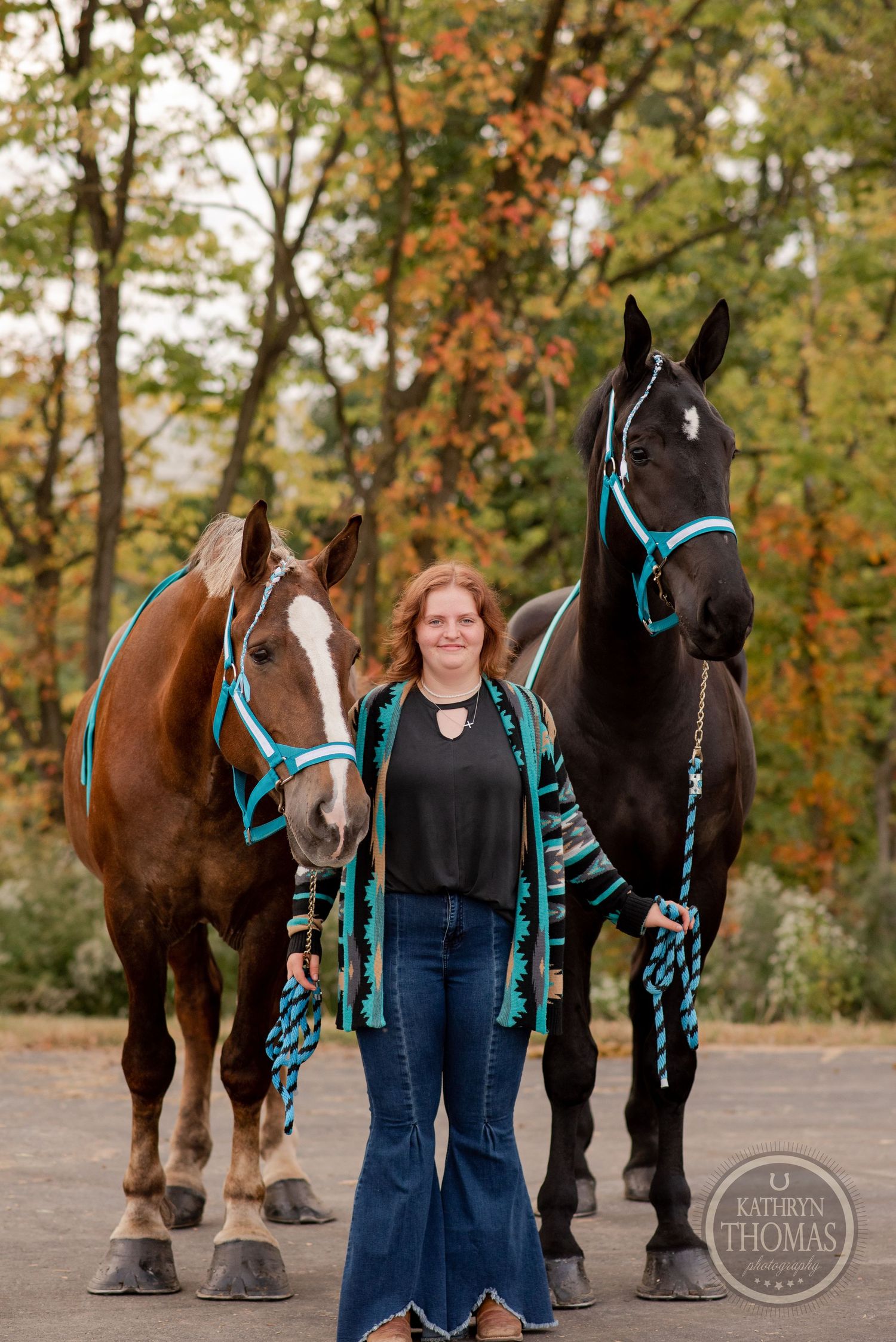Two horses with turquoise halters and handler pose outdoors in autumn setting.