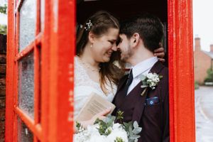 Intimate moment between newlyweds inside a red British phone booth.
