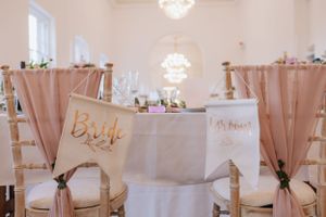 Wedding reception table with elegant bride and groom chair signs in rose gold.