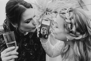 Black and white photo of wedding party sharing champagne and taking selfies.