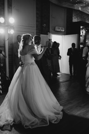 A couple shares their first dance in a dimly lit reception venue with flowing white wedding gown.