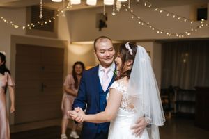 First dance moment under string lights with guests watching in the background.
